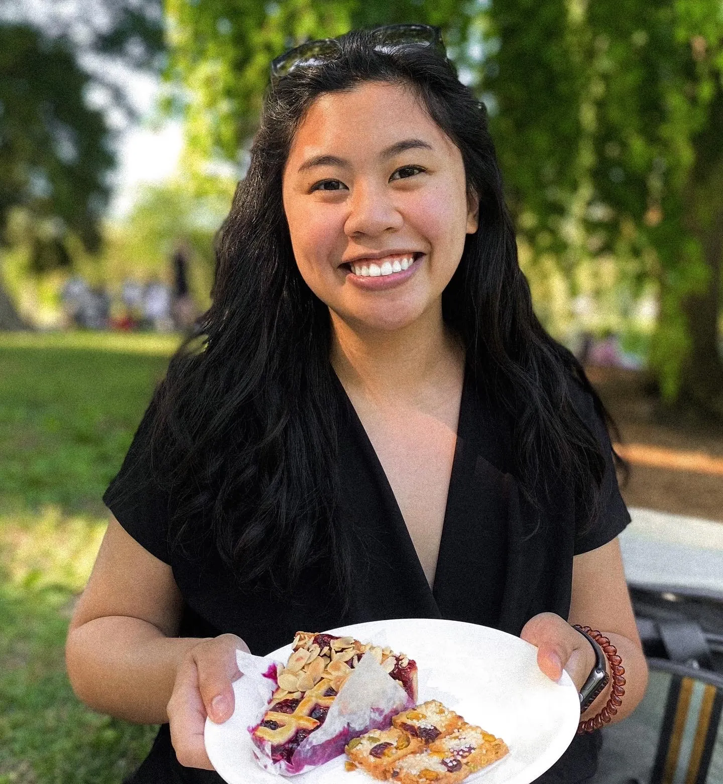 Bianca smiling outdoors with a plate of baked desserts